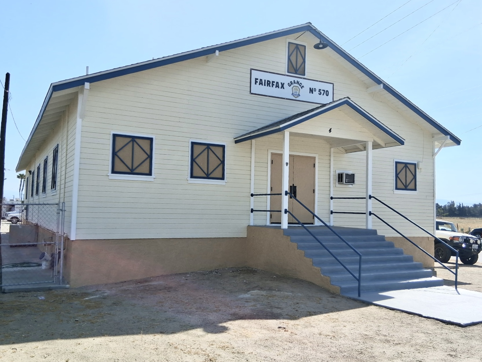 Side view of the repainted Fairfax Grange hall with clean siding and navy accents